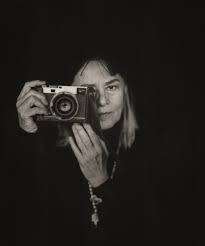 Black and white photograph of Donna Ferrato with a camera.